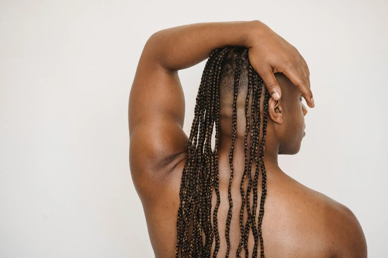 Long box braids from behind, a hand resting on the crown