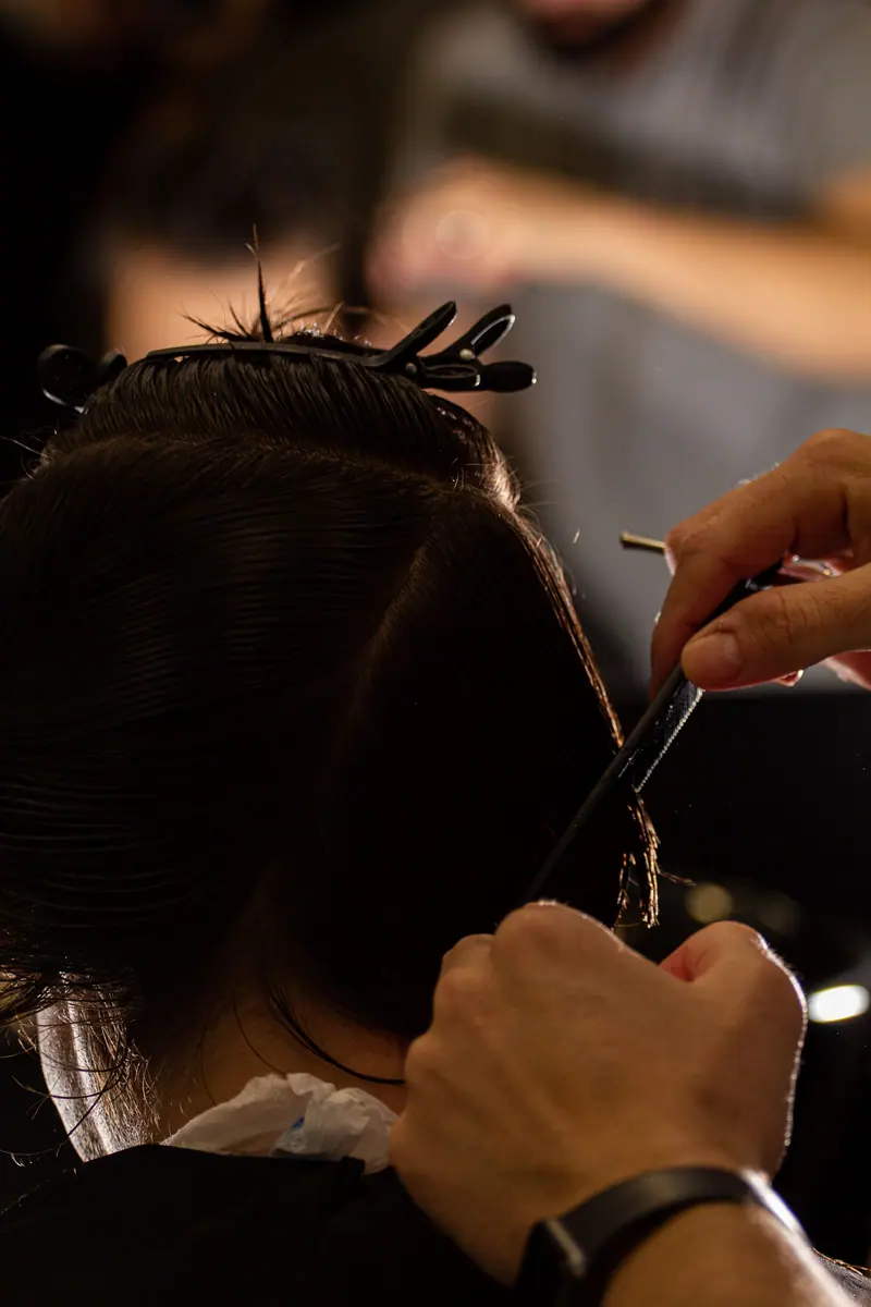 A hairdresser carefully cuts hair, focusing on precision and style.