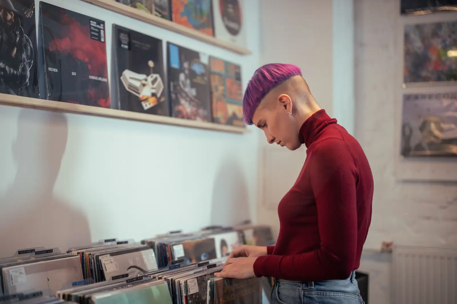 Rowan Volk, with a purple undercut, digging through records in a shop