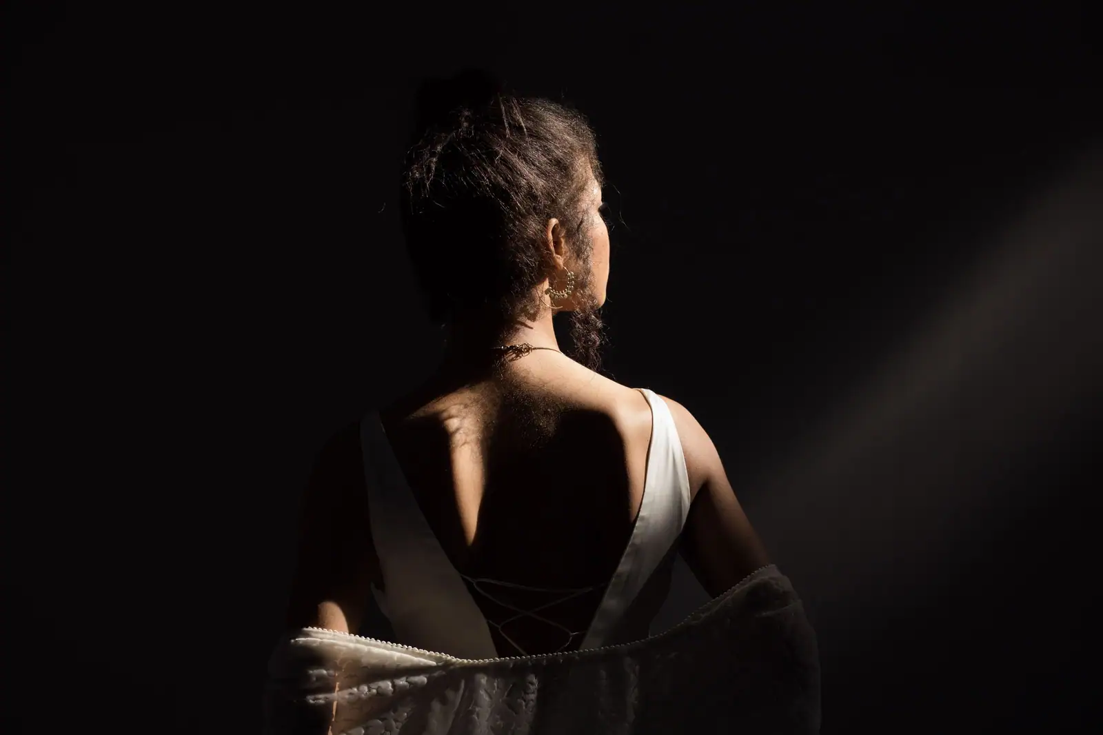 A client’s defined curly updo from behind, lit low against a dark wall