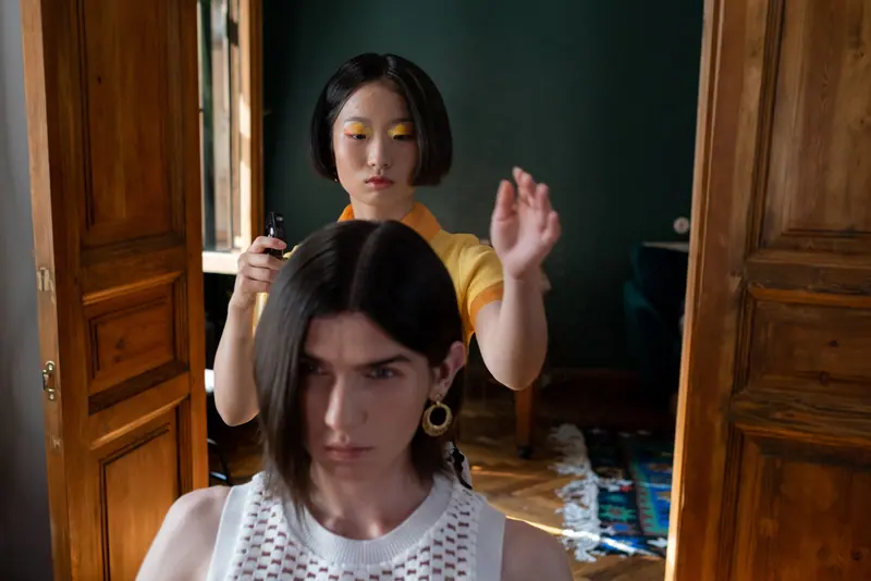 A hairdresser styling a client's hair in a salon with modern interior.