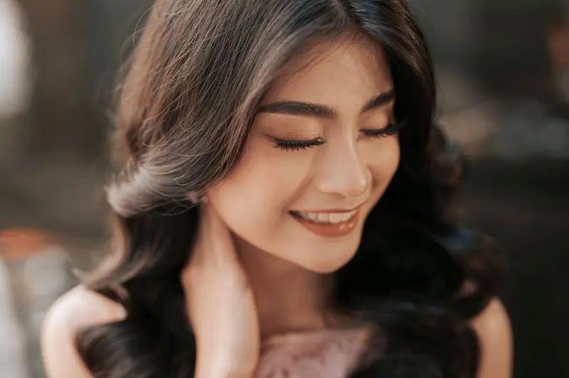 Close-up of a smiling woman with closed eyes, exuding natural elegance and beauty.