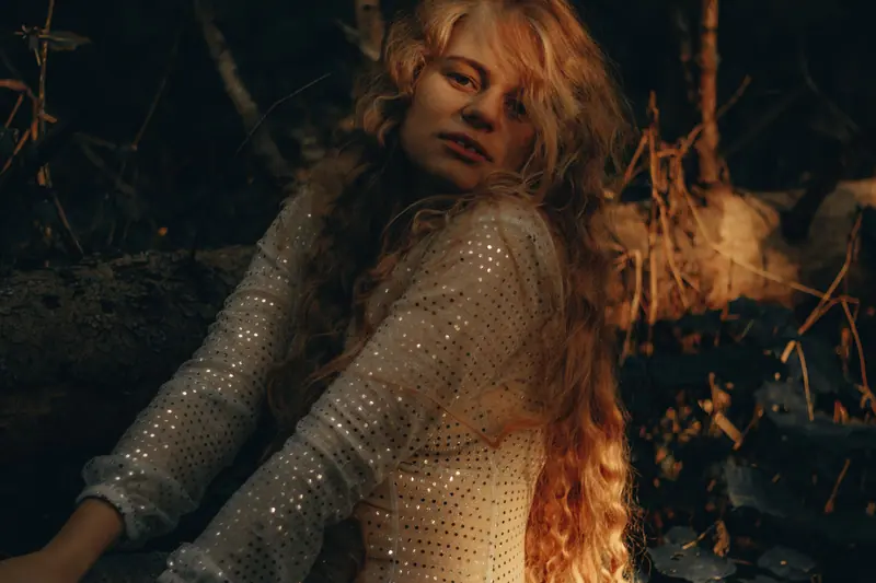 A captivating portrait of a blonde woman with curly hair illuminated by soft natural light.