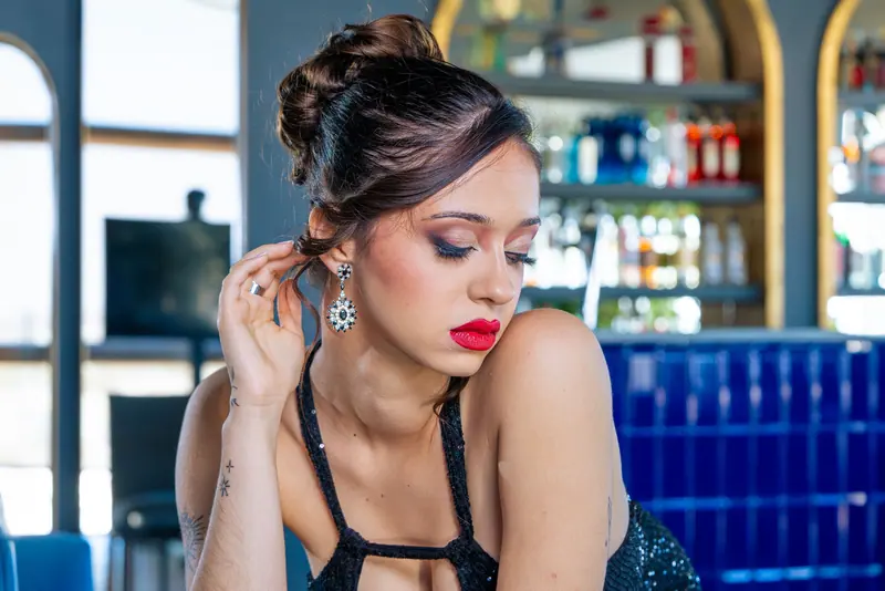 Portrait of a glamorous woman with elegant makeup posing indoors at a stylish bar.
