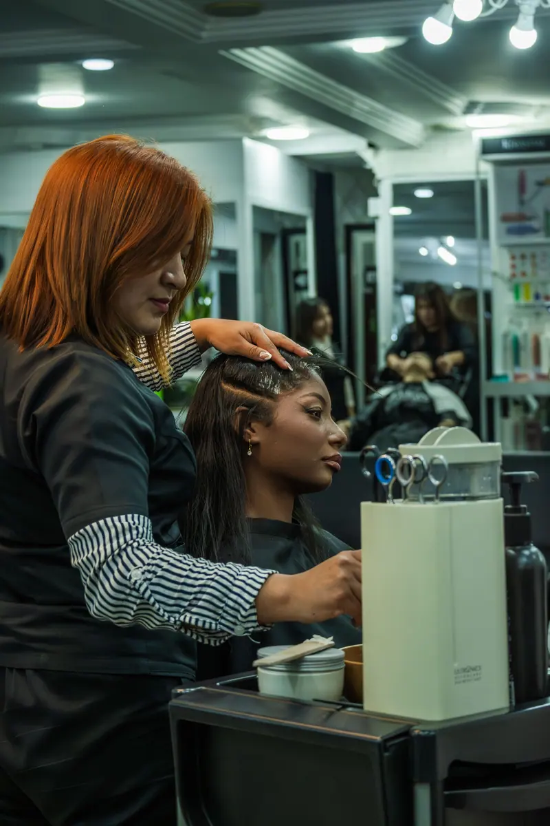 Professional hairdresser styles client's hair in a modern salon in Cuenca, Ecuador.
