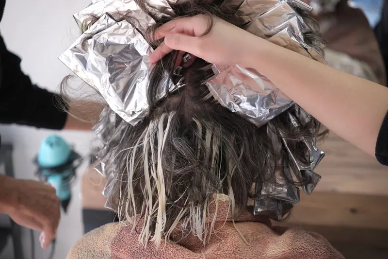 A detailed shot of hair coloring process using foils at a salon in İzmir, Türkiye.