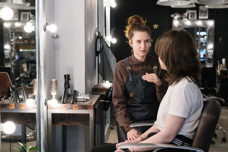 Hair stylist providing consultation to client in a modern salon setting.