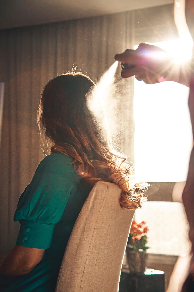 Backlit hairstyling scene with sunlight illuminating a woman in a salon setting.