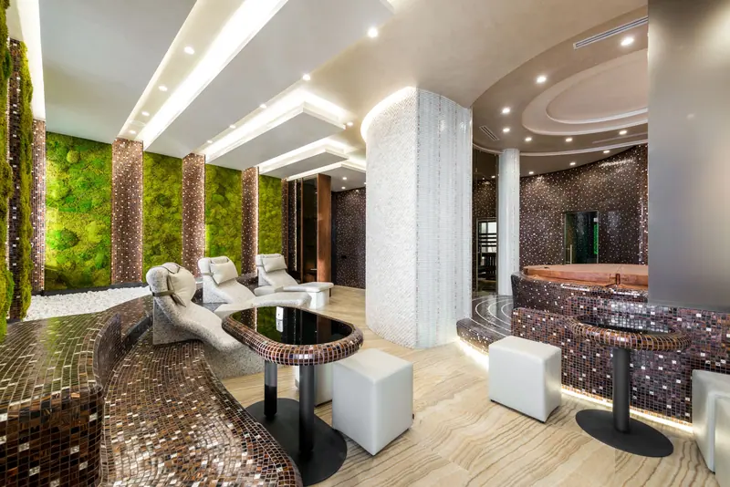 Sophisticated spa interior featuring luxurious seating and a vibrant green wall, perfect for relaxation.