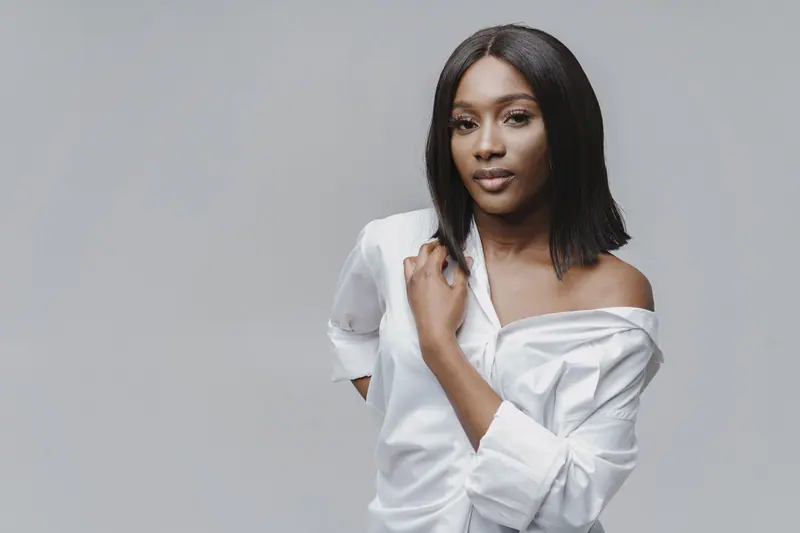 Stylish portrait of an elegant woman in a studio setting wearing a white shirt.