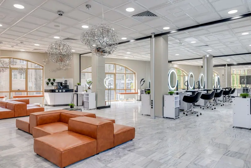 Bright and airy hair salon with orange sofas and marble floor, ideal for chic interiors.