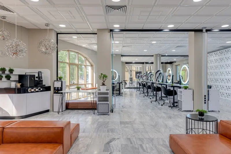 Bright and spacious modern beauty salon with stylish design, featuring a coffee station and makeup stations.