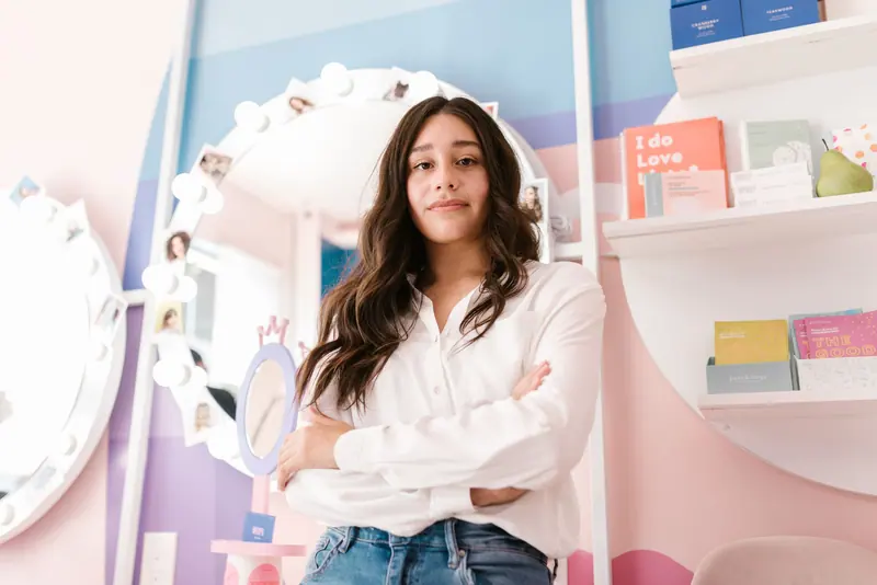 A stylish woman standing confidently in a modern hair salon with a vibrant, welcoming environment.