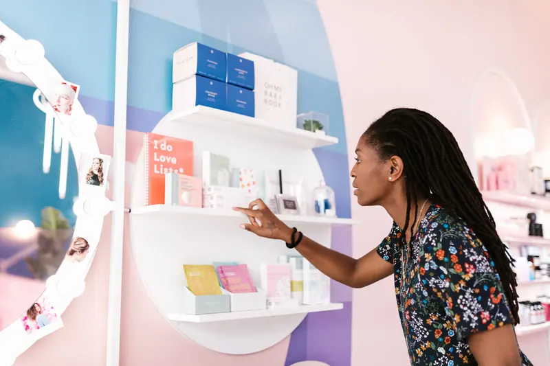 A woman with dreadlocks browsing cosmetics at an upscale salon.