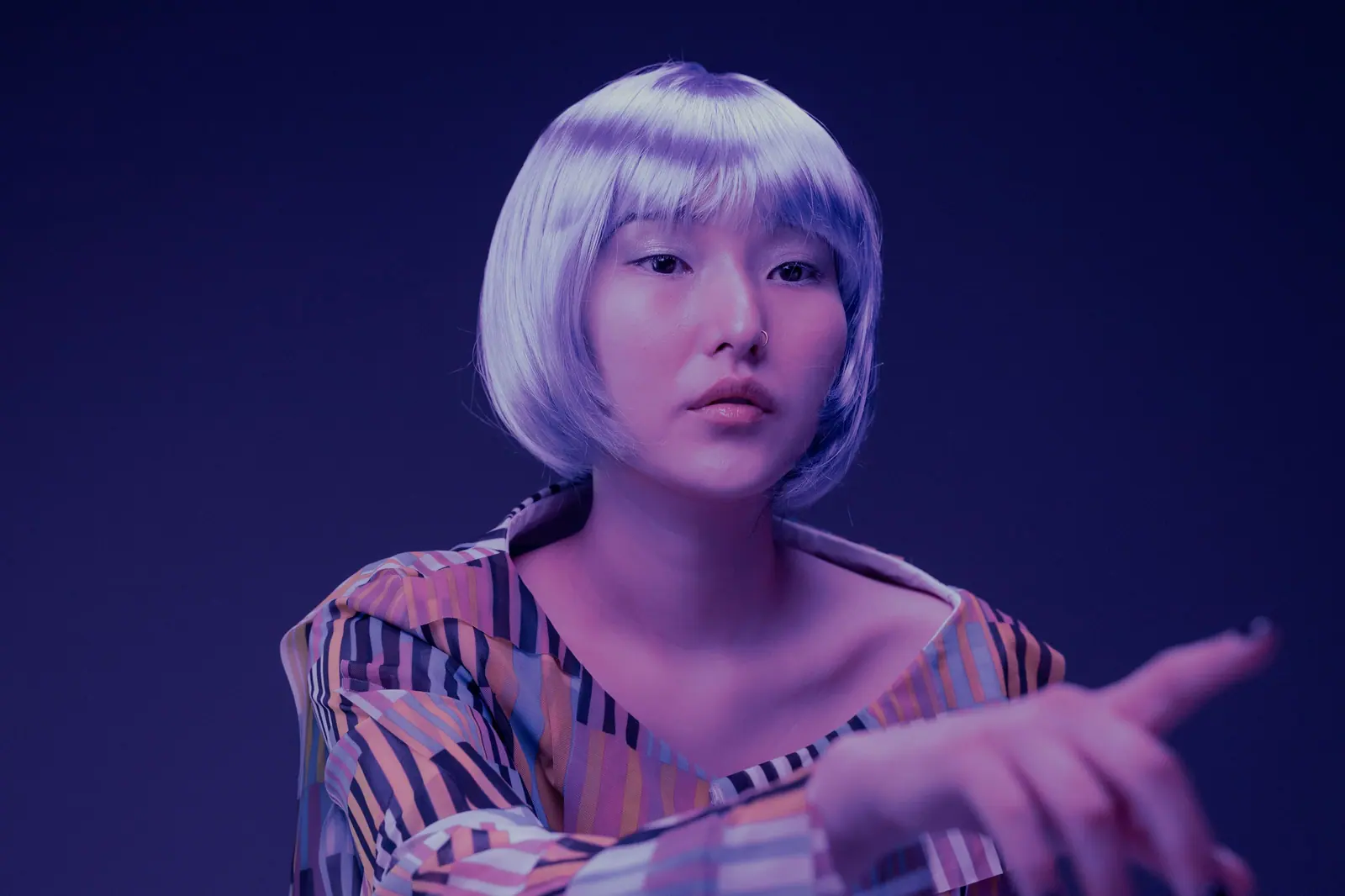 Woman with a lilac bob in violet light against a deep indigo backdrop