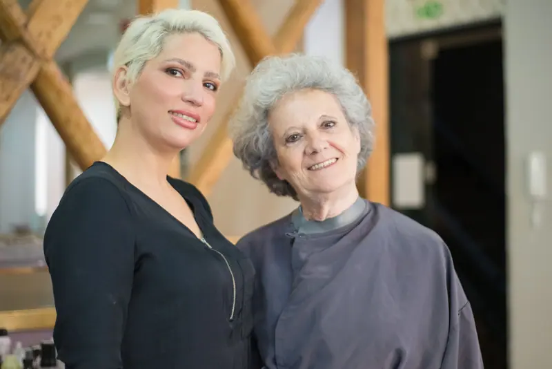 Smiling hair stylist with a happy elderly client in a modern salon setting