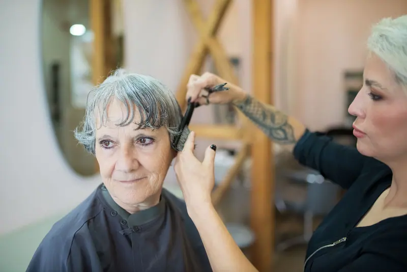 Elderly woman getting a stylish haircut by a professional hairdresser in a salon.