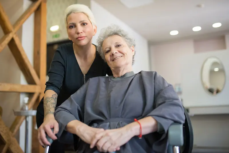 Senior woman enjoying a hairdressing session at a salon in Portugal, with a friendly stylist.