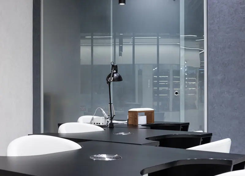 Sleek and contemporary beauty salon interior featuring black tables and white chairs with natural lighting.