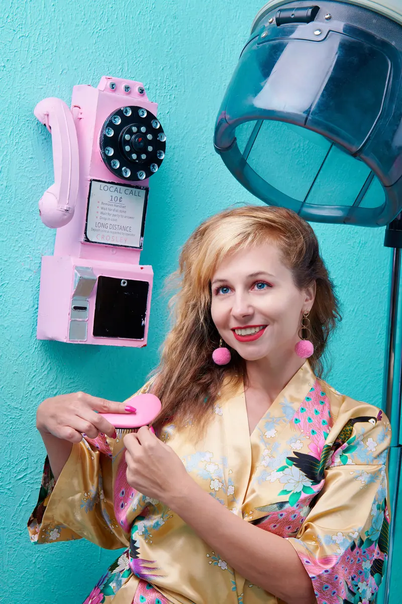 Brushing out by the pink telephone and hood dryer