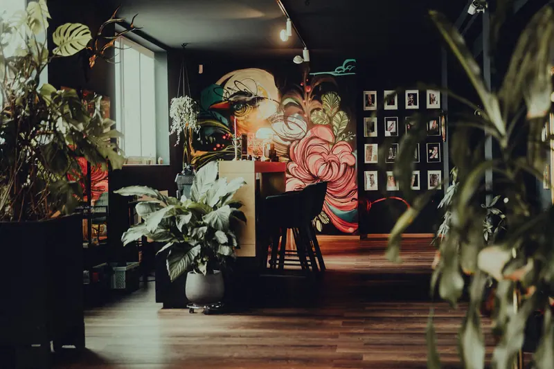 Cozy tattoo shop interior with lush plants and vibrant mural art in Keltern, Germany.