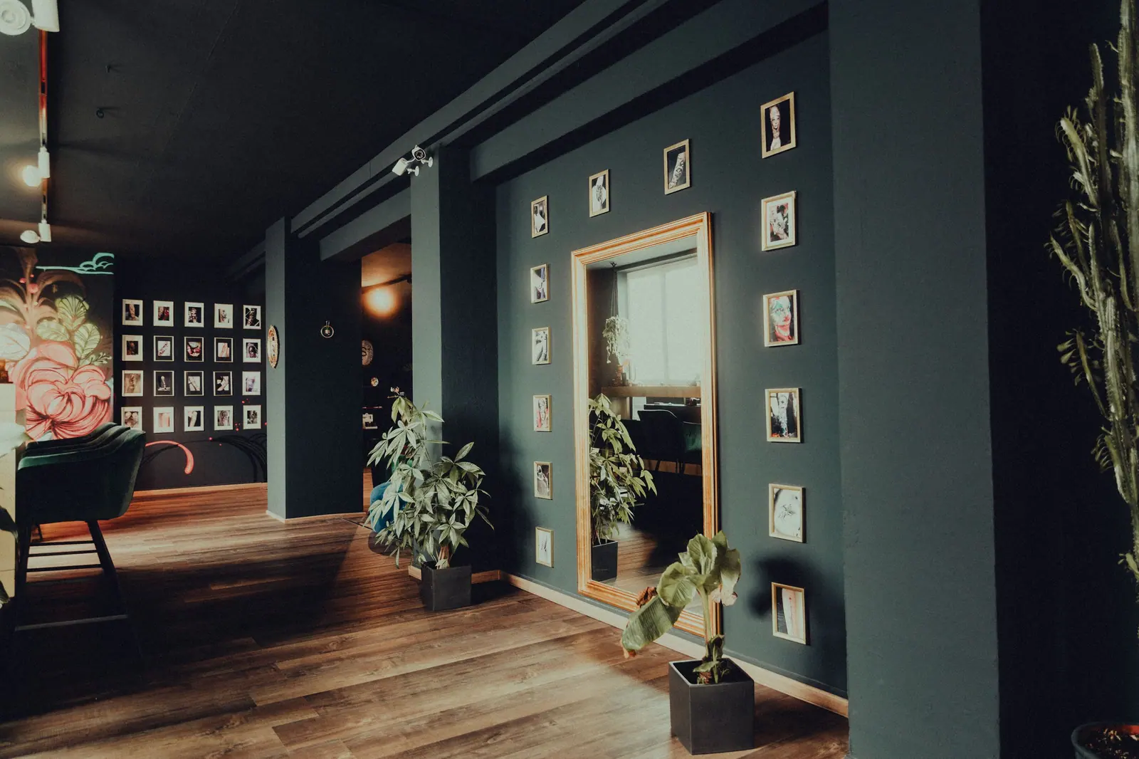 Dark-green salon suite filled with potted plants, framed photos and warm wood floors