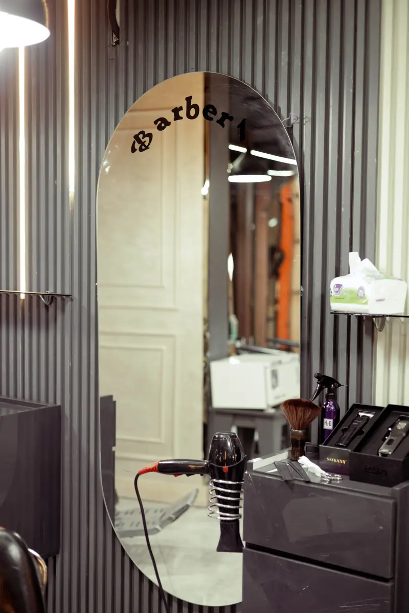 Barber shop interior featuring a stylish mirror, grooming tools, and sleek decor.