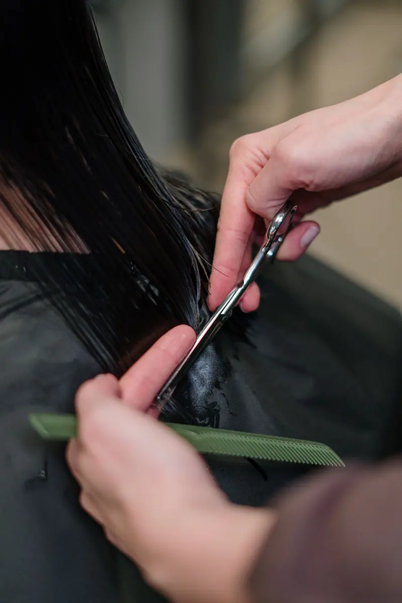Close-up of a hairdresser cutting black hair in a salon, focusing on precision and style.