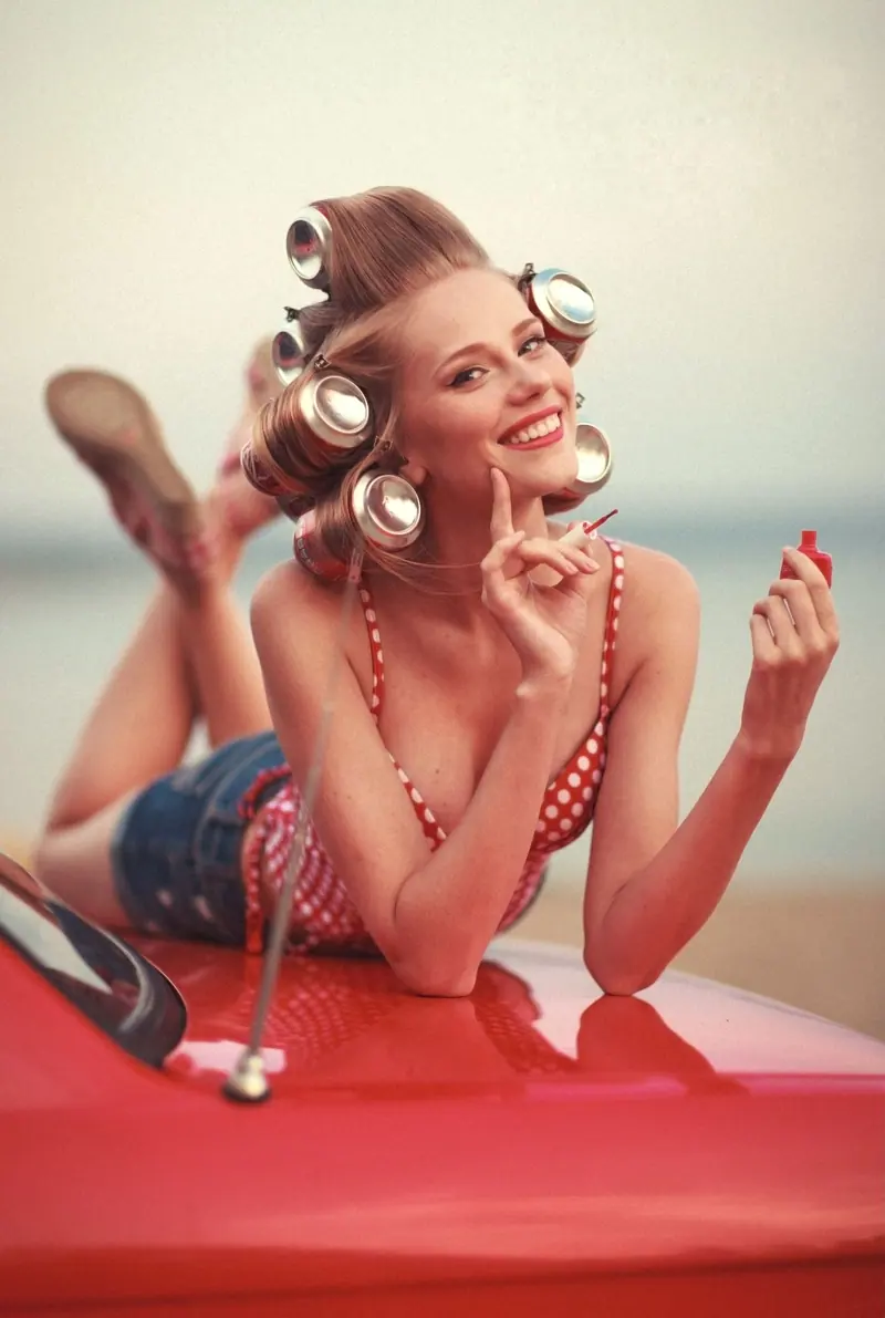 Pin-up in rollers on a red car