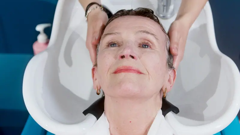 An elderly woman getting a hair wash at a salon, enjoying a relaxing grooming service.