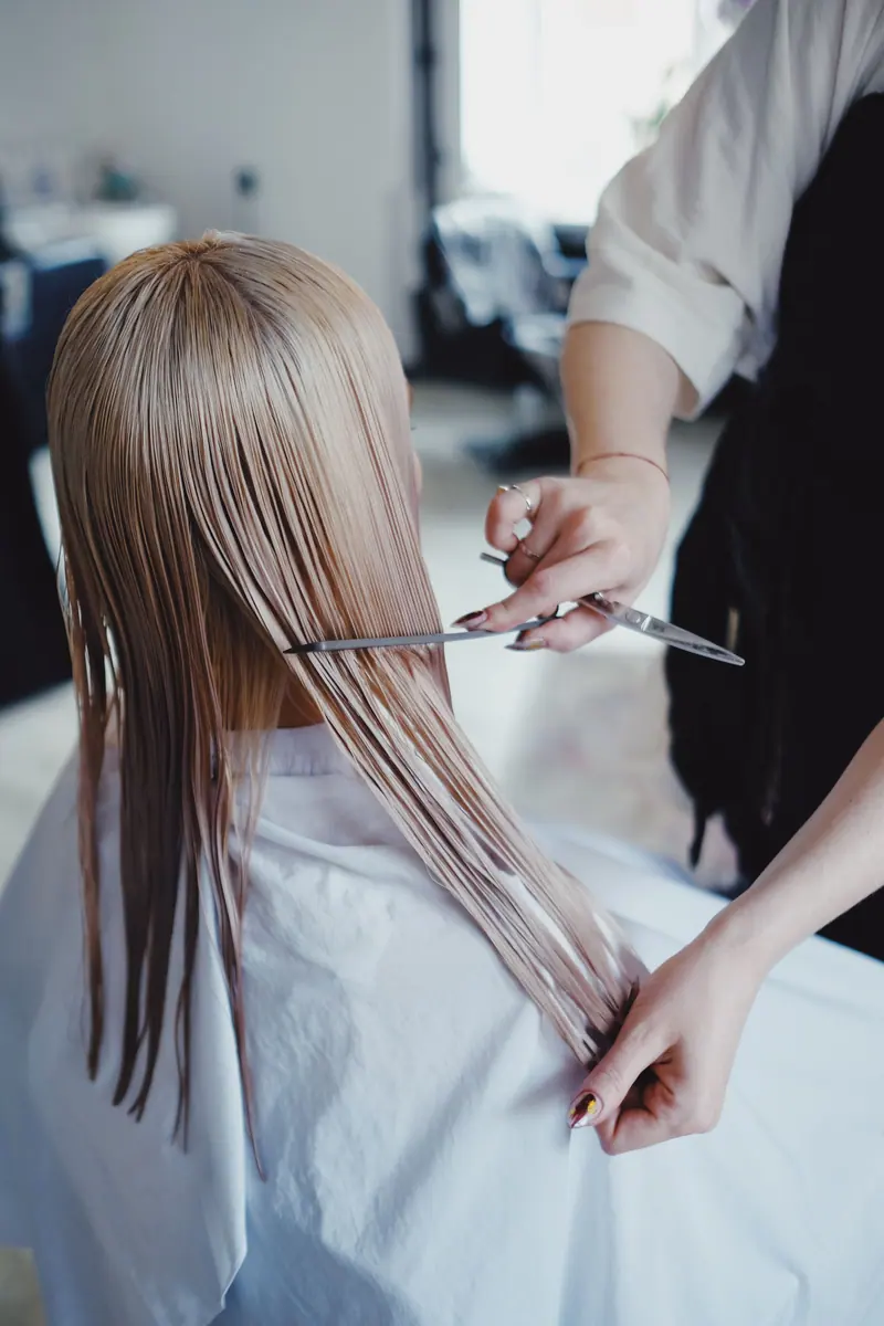 Blond woman receiving a professional haircut in a modern salon, showcasing precise scissor work.
