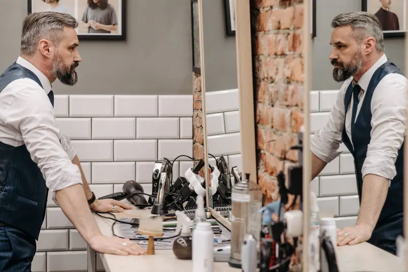 Barber and client reflected in a vintage mirror inside the suite