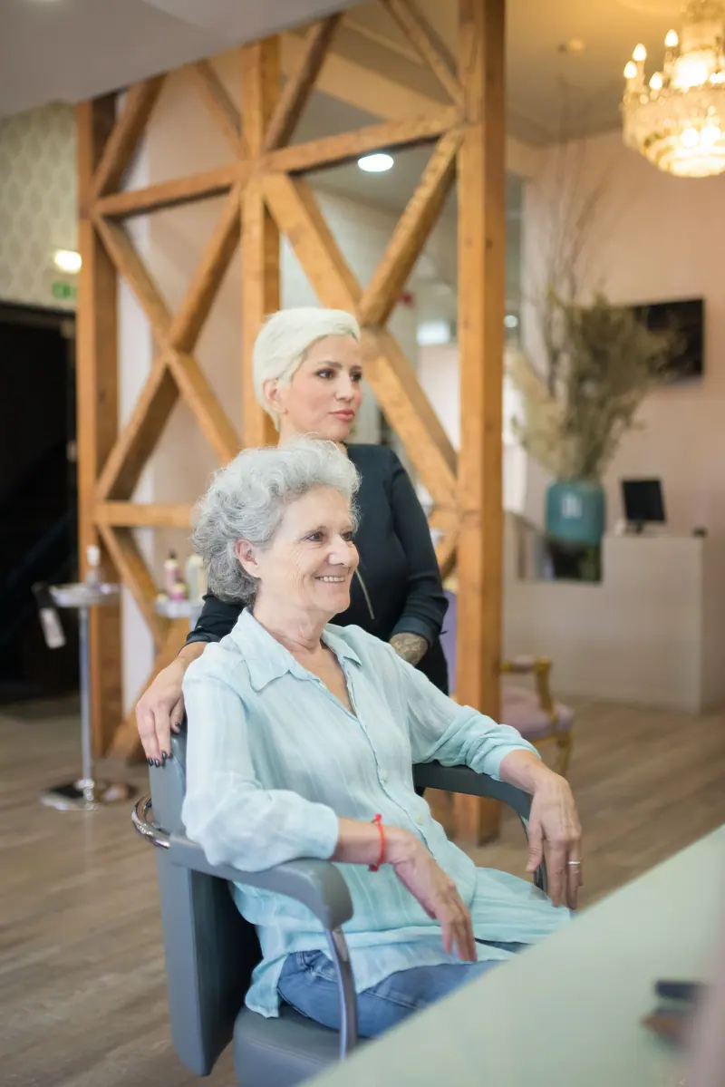 Senior woman at a hair salon with a stylist, creating a welcoming atmosphere.