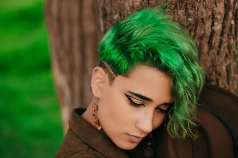 Bright green curls with an undercut against a tree trunk