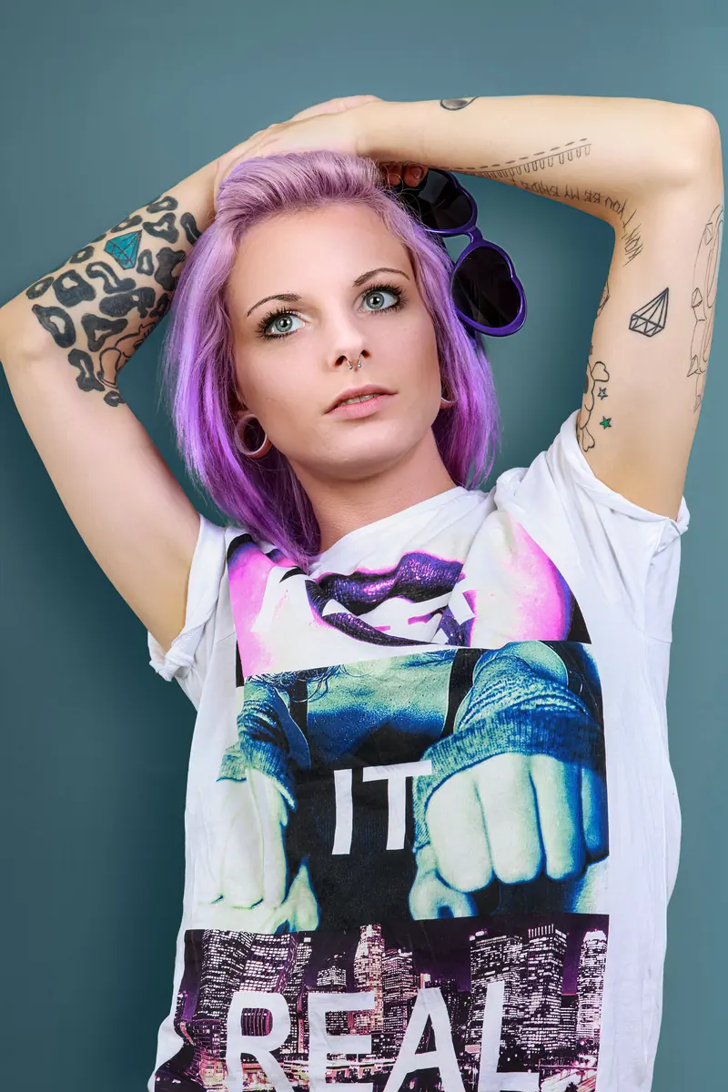 Lilac and purple hair pinned up, with tattooed arms