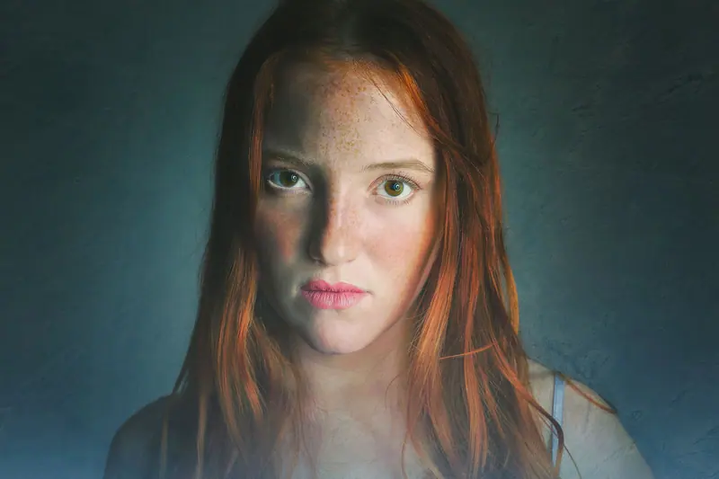 Copper hair and freckles in moody light