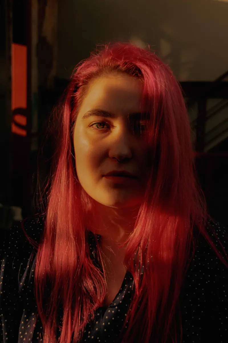 Coral-pink hair in warm lamplight