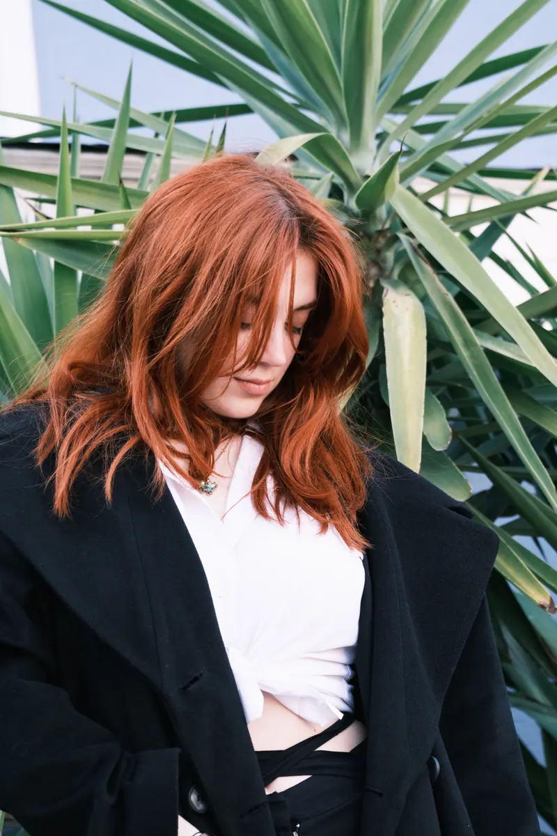 Rich auburn hair against green foliage