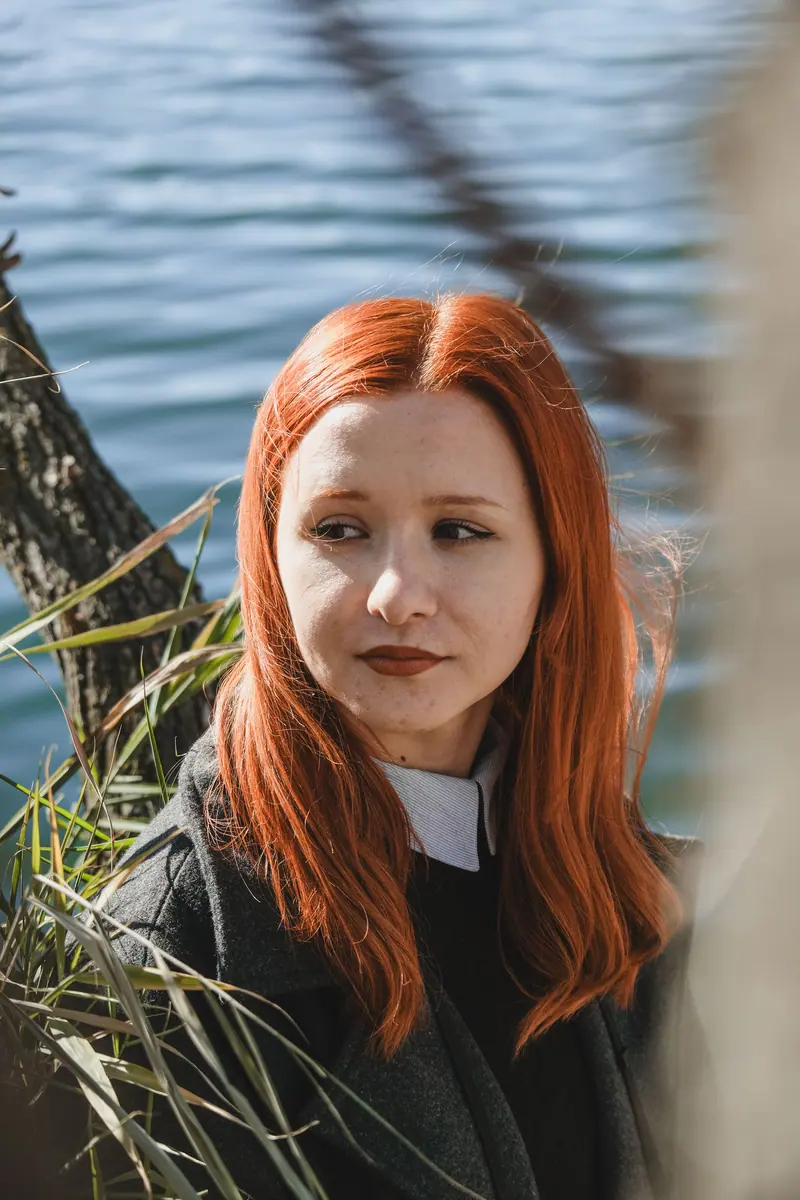 Long copper hair by a lake