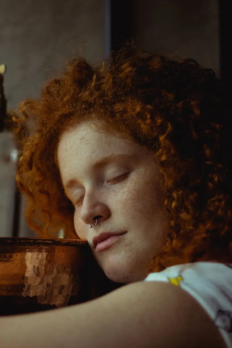 Close-up of tight red curls and a gold nose ring