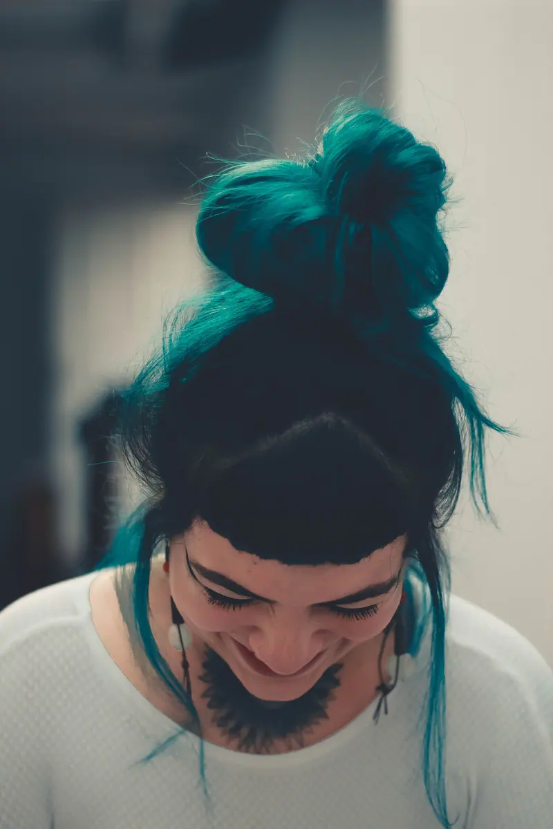 Smiling client with teal hair and tattoos