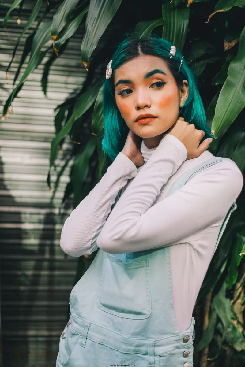 Teal hair framed by tropical leaves