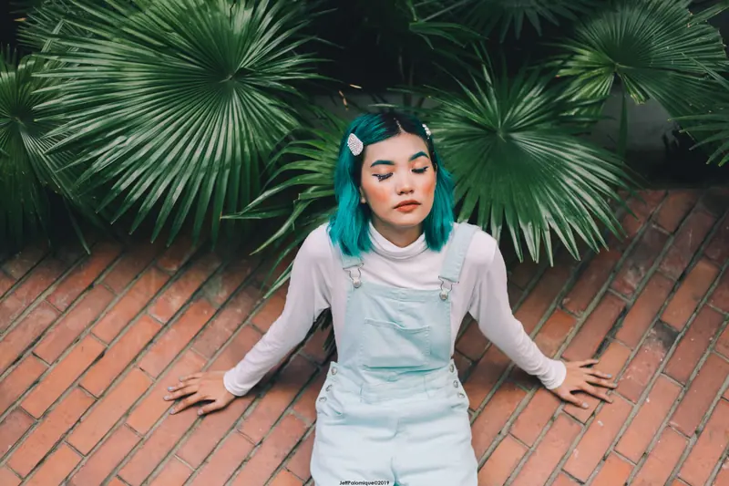 Teal-green hair against lush leaves