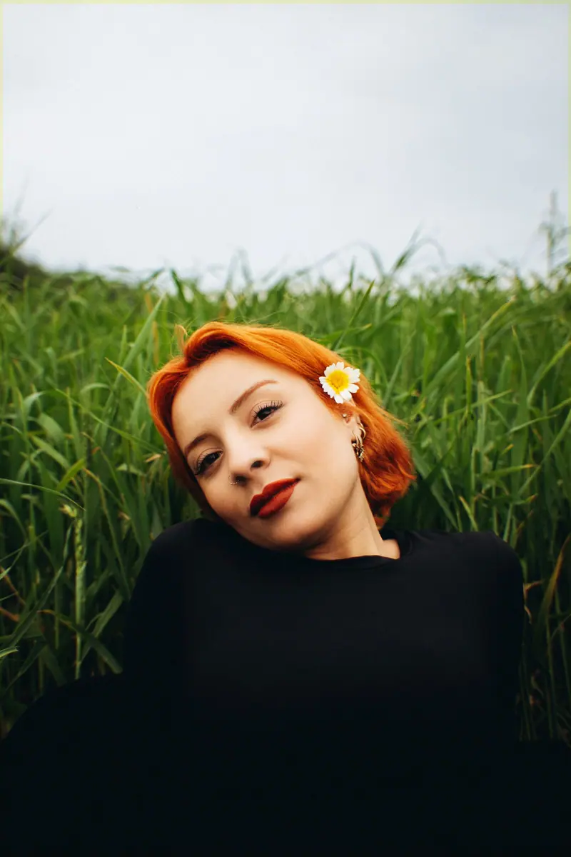 Red hair with a daisy in a green field