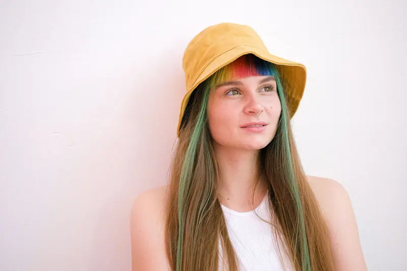 Long hair with green and rose panels under a yellow hat