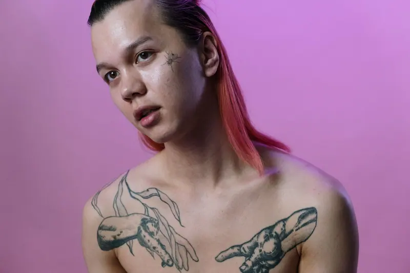 Tattooed client with pink hair against a pink backdrop