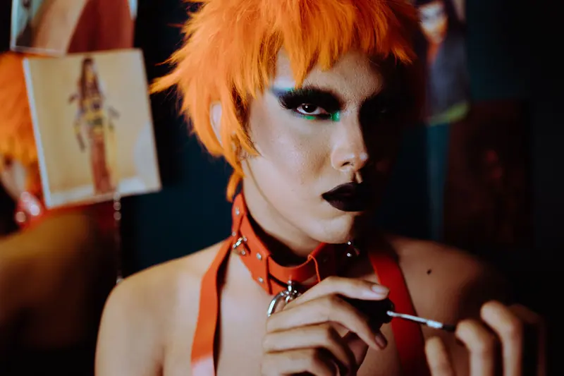 Orange stage wig and bold makeup