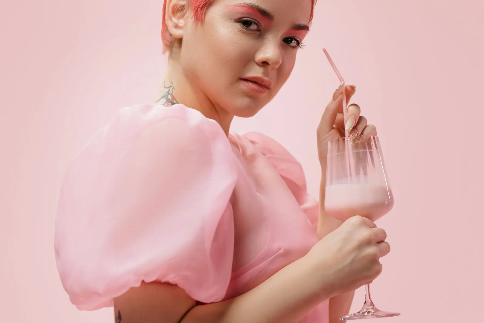 Portrait of a woman in pink enjoying a strawberry milkshake, capturing a vibrant and modern aesthetic.