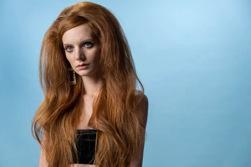 Big ginger waves against a powder-blue backdrop