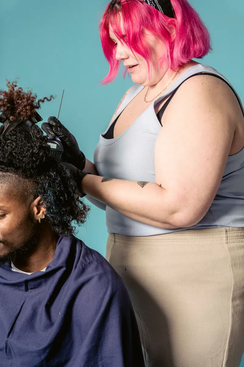 Pink-haired stylist styling curly hair